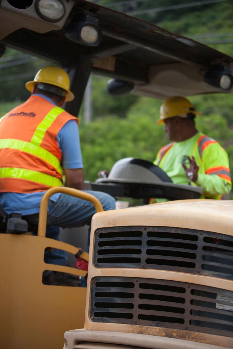 Two Grace Pacific crew members working beside paving equipment.