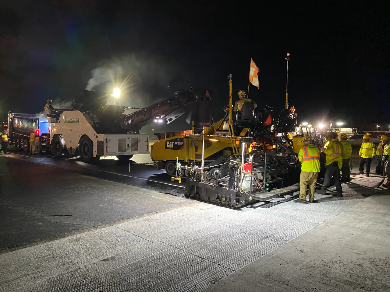 Asphalt paving equipment and crew working on Runway 8L at night.