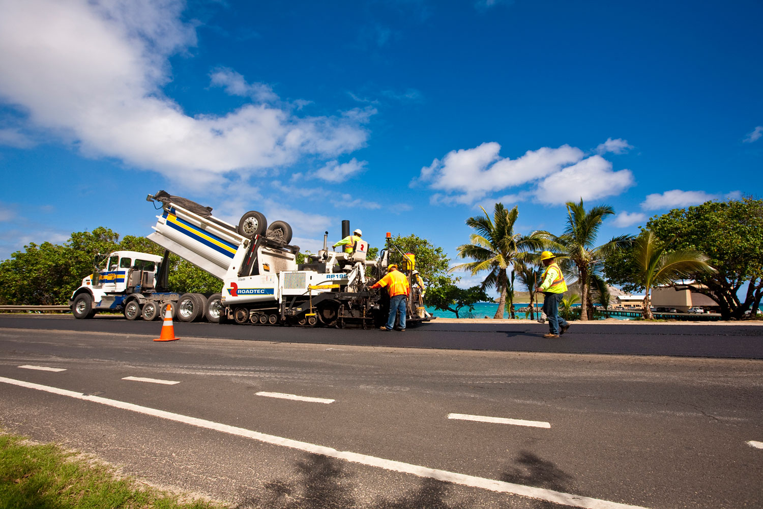 Asphalt paving crew resurfacing a coastal highway in Hawaii