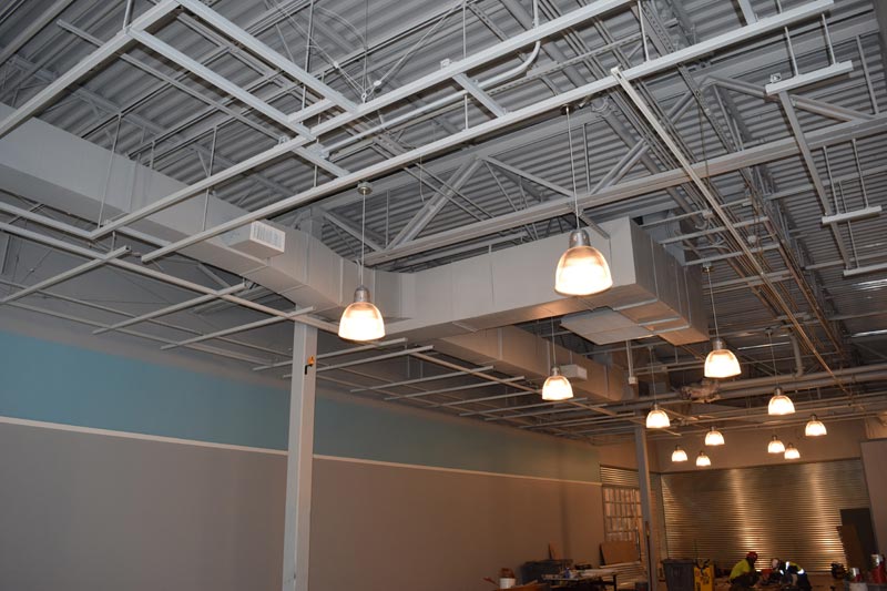 Installed overhead framing, ducts and suspended lights inside a building.