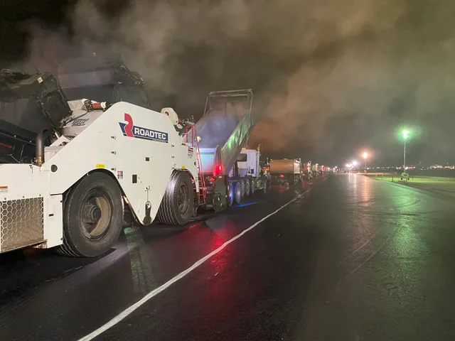 Paving equipment and trucks under runway lights